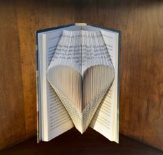 an open book with pages folded into the shape of a heart