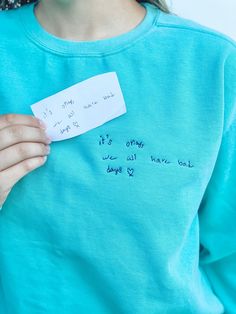 a woman holding a piece of paper with writing on it