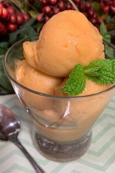 two scoops of ice cream sit in a glass bowl with mint leaves on top