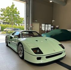 a green sports car parked in a garage next to another vehicle on the other side