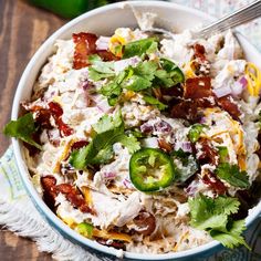 a blue bowl filled with chicken salad next to green peppers and jalapenos