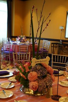 an elegant centerpiece is displayed on a table in a banquet hall with gold plates and silverware