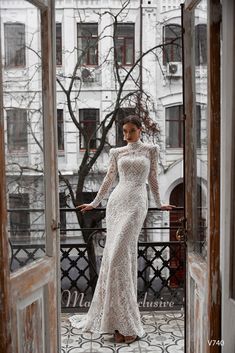 a woman is standing in an open doorway wearing a long sleeved wedding dress and heels