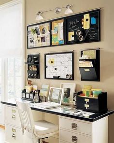 a home office with white furniture and lots of framed pictures on the wall above it