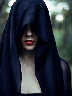 a mannequin dressed in black with a hood over her head and red lips