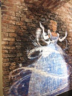 a brick wall with a drawing of a woman in a white dress on it's side