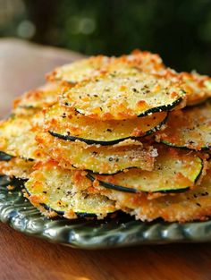 zucchini chips stacked on top of each other on a green plate with sprinkled parmesan cheese