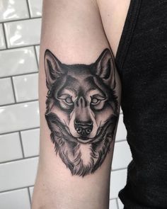 a black and white wolf tattoo on the arm