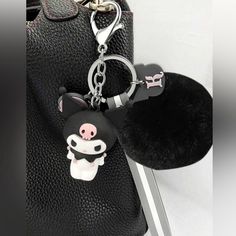 a black purse with a keychain that has a small pig on the front