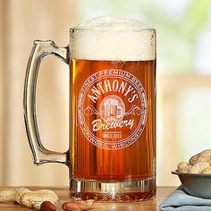 a beer mug sitting on top of a wooden table next to some cookies and crackers