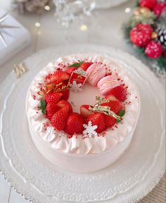 a white cake topped with strawberries on top of a table next to christmas decorations