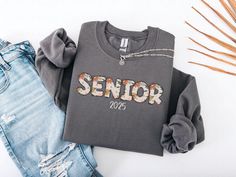 a shirt with the word senior on it next to some jeans and a pair of shoes