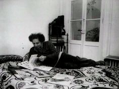 a man laying on top of a bed reading a book