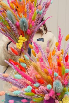 a woman holding a bunch of colorful flowers