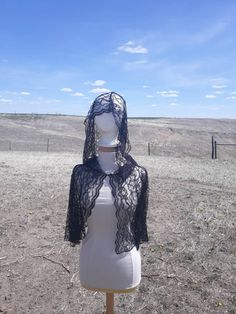 a mannequin wearing a black lace top in the middle of an open field