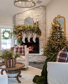 a living room decorated for christmas with stockings and wreaths on the fireplace mantel