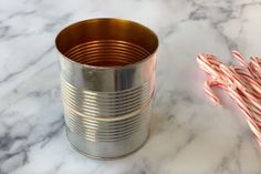 a candy cane next to a tin can on a marble counter top with white and red stripes