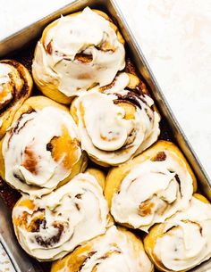 a pan filled with cinnamon rolls covered in icing