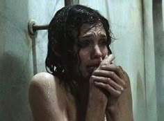 a naked woman sitting in the shower with her hand under her chin