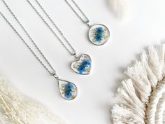 Our Forget-Me-Not Flower Pendant Necklace is made with 18k gold plating.  The silver pendant is 925 silver plated.   Each pendant holds delicate dried pressed Forget-Me-Not flowers, safely encased in clear resin and adorned with beautiful Queen Anne's lace and glittering gold flakes. 🌸 This necklace is perfect for any occasion, whether you're attending a fancy event like a wedding or simply hanging out with friends; it's the perfect accessory. Its simple, elegant style pairs well with everythin Blue Sterling Silver Birth Flower Jewelry, Blue Sterling Silver Jewelry With Birth Flower, Silver Hypoallergenic Flower Necklace, Blue Flower Jewelry With Natural Inclusions, Blue Sterling Silver Necklace With Flower Charm, Blue Necklace For Mother's Day, Blue Round Necklace For Mother's Day, Flower-shaped Necklaces With Pressed Flowers For Anniversary, Blue Flower Charm Jewelry As Gift For Her