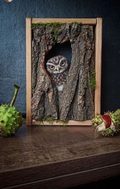 an owl is peeking out of a hole in the bark of a tree with green leaves