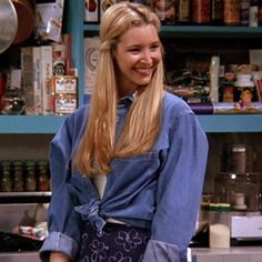 a woman with long blonde hair is standing in front of a counter and smiling at the camera