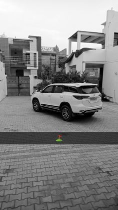 a white car parked in front of a building next to a brick walkway and parking meter