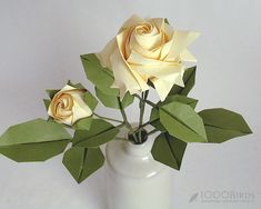 three yellow roses in a white vase with green leaves