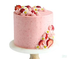 a pink cake with strawberries and daisies on top