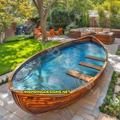 a large wooden boat sitting in the middle of a garden next to a swimming pool