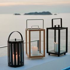 three lanterns sitting on top of a table next to each other with candles in them