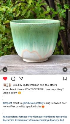 a green and white bowl sitting on top of a wooden table next to some trees