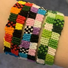 three different bracelets on someone's arm, one is multicolored and the other is white