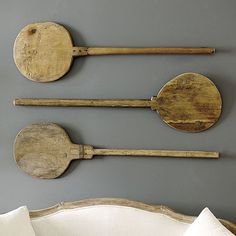 four wooden utensils are hanging on the wall next to a white couch and pillow