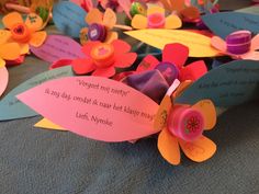 colorful paper flowers with words written on them sitting on a blue cloth covered tablecloth