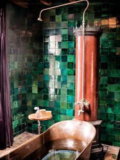 a bath tub sitting next to a green tiled wall