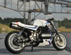 a white and blue motorcycle parked next to a body of water with power lines in the background