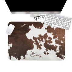 a computer mouse pad with a brown and white cow print on it, next to a keyboard