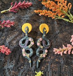 two pairs of earrings sitting on top of a table next to flowers and other items