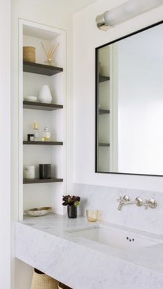 a white bathroom sink sitting under a large mirror