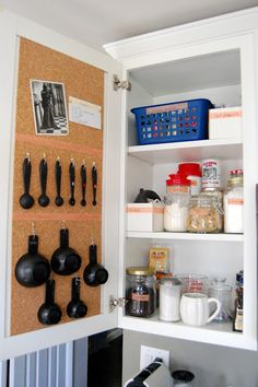 an open cabinet with utensils hanging on the wall