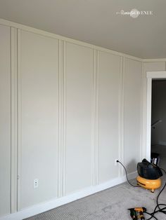 an empty room with white paneling and a blow dryer on the floor next to it