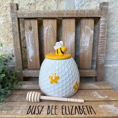 a yellow and white bee honey jar sitting on top of a wooden bench