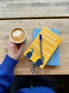 a person sitting at a table with a cup of coffee and a book on it