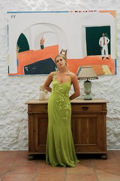 a woman in a green dress standing next to a painting