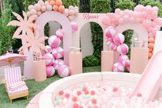 there is a pink and white pool with balls in it that has been set up for an outdoor birthday party