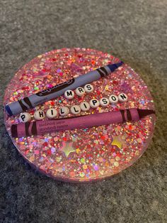 two crayons are sitting on top of a glitter covered plate with words written in them