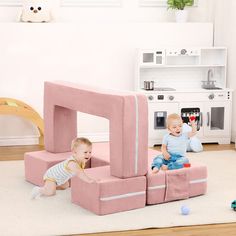 two toddlers playing in a play room with pink furniture and toys on the floor