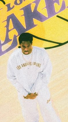 a man standing on top of a basketball court with his hands in his pockets and wearing white sweatpants