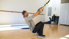 a man holding onto a rope while standing on the floor in front of a yoga mat